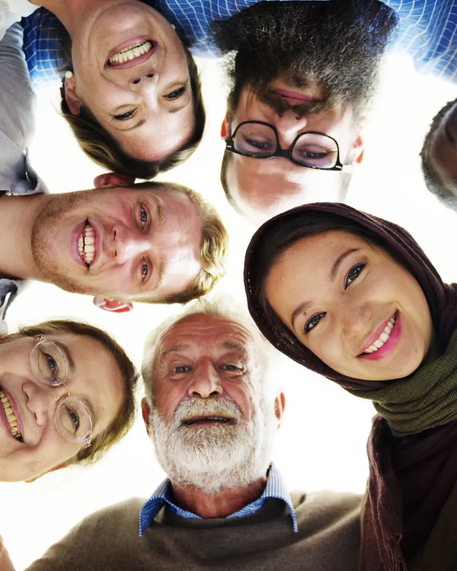 Smiling people of different ages and backgrounds in a circle, looking down at the camera