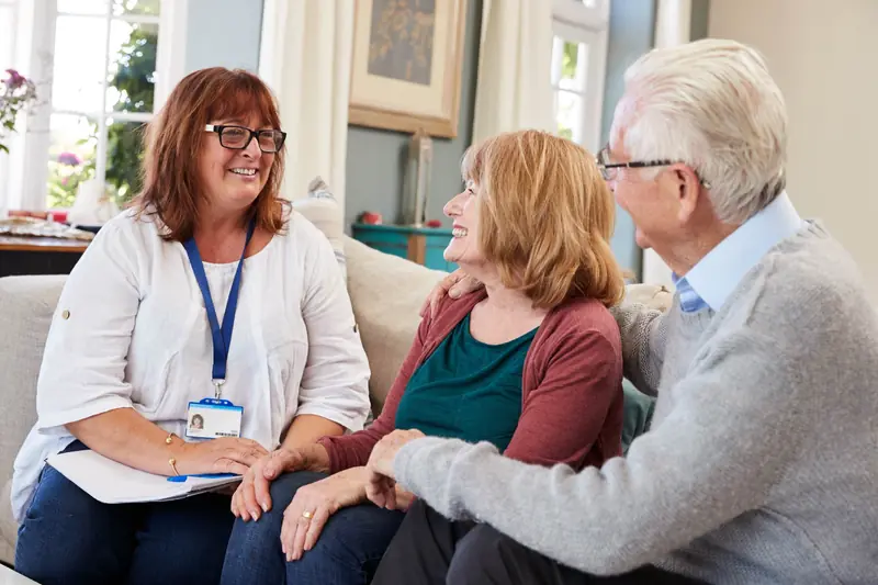 Support worker chatting with an older couple in their living room