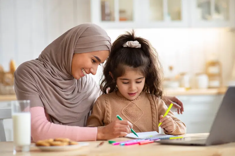 Mother and young daughter drawing together at the kitchen table